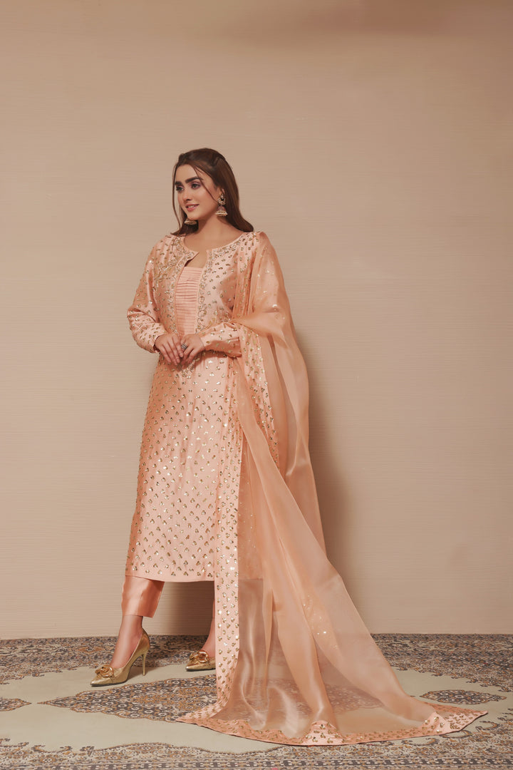  Adorn yourself in peach sheesha silk with exquisite hand-embellished zardozi and sequence work, paired perfectly with elegant straight pants.