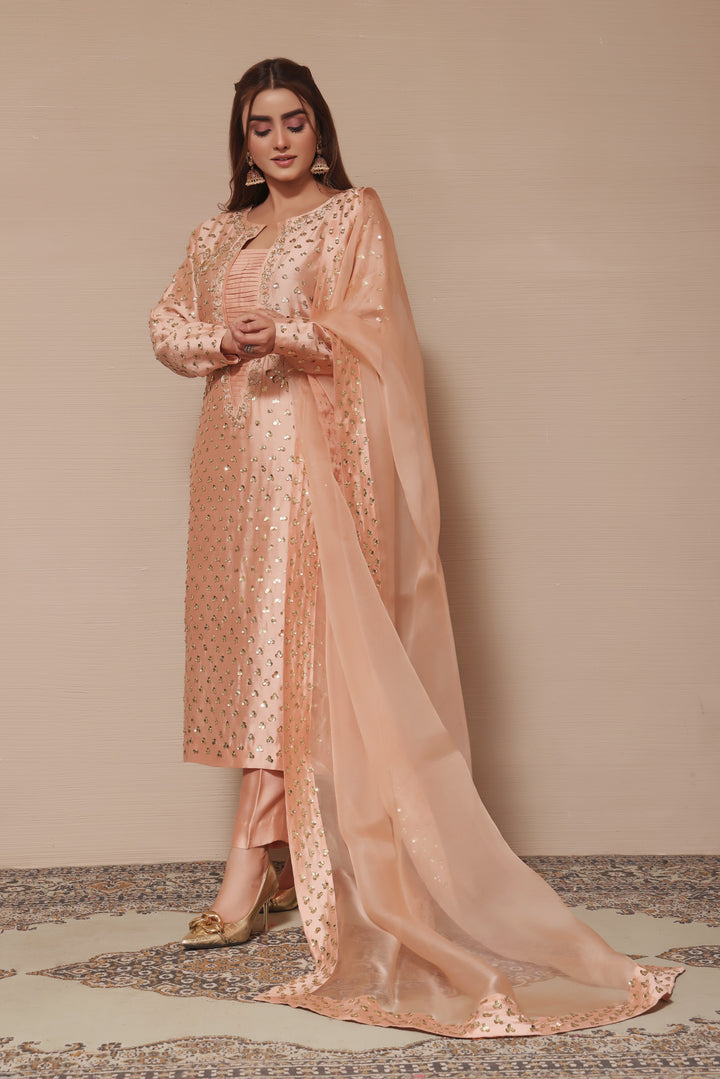  Adorn yourself in peach sheesha silk with exquisite hand-embellished zardozi and sequence work, paired perfectly with elegant straight pants.