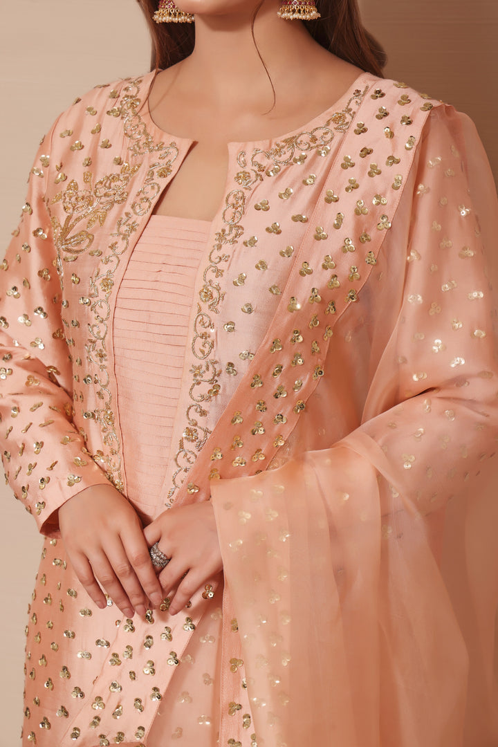  Adorn yourself in peach sheesha silk with exquisite hand-embellished zardozi and sequence work, paired perfectly with elegant straight pants.