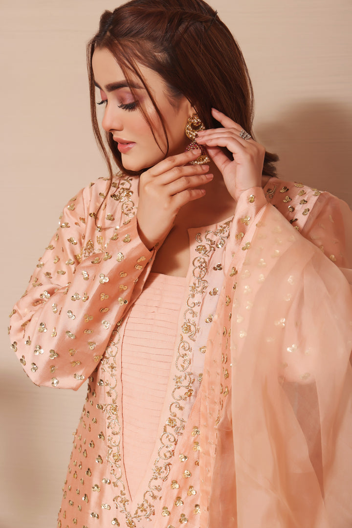  Adorn yourself in peach sheesha silk with exquisite hand-embellished zardozi and sequence work, paired perfectly with elegant straight pants.