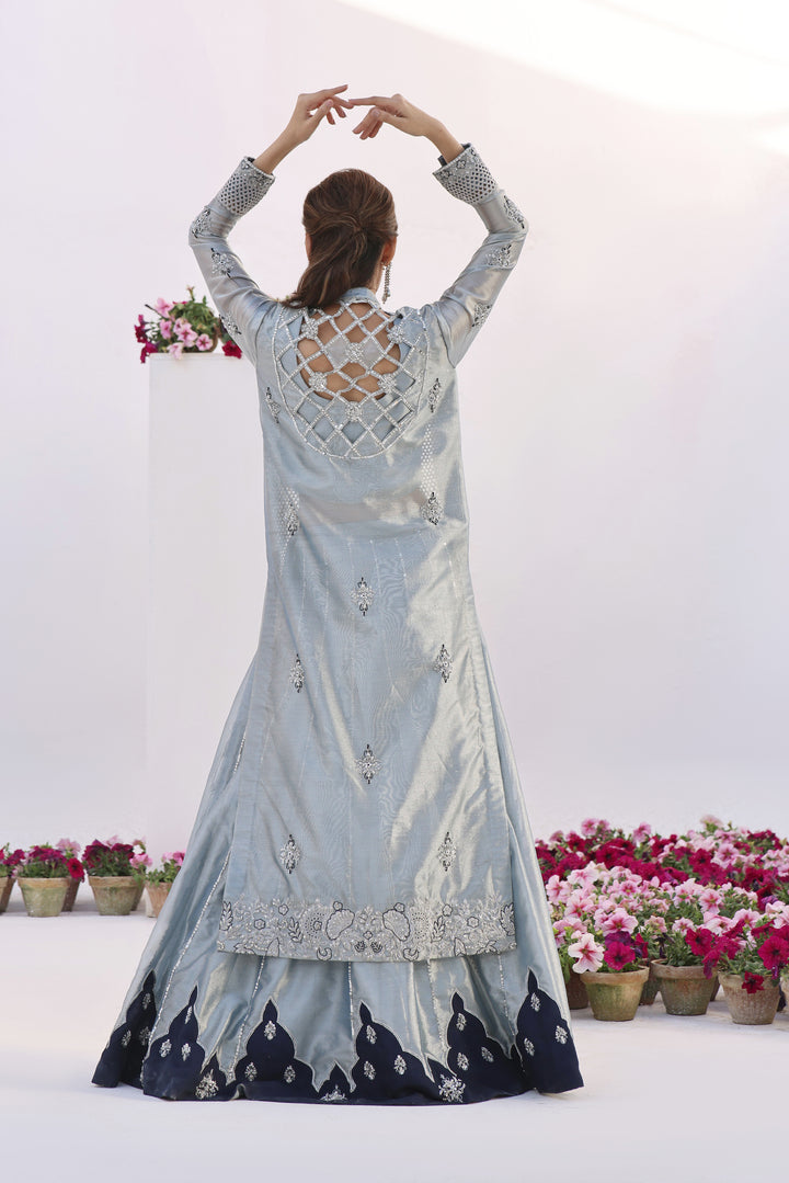  Step into elegance with Fiza by Mona Imran, crafted from luxurious lambha tissue with mesmerizing cutout pattern jaal adorned with pearls and diamonte work.