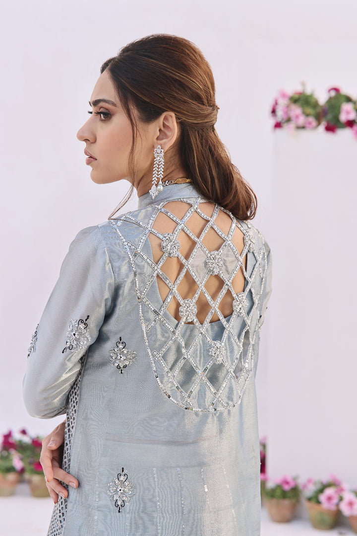  Step into elegance with Fiza by Mona Imran, crafted from luxurious lambha tissue with mesmerizing cutout pattern jaal adorned with pearls and diamonte work.