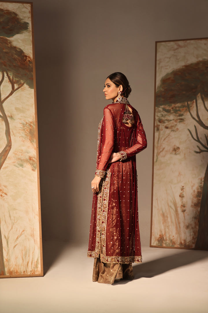  Step into timeless elegance with Gulabposh by Mona Imran, featuring a deep maroon kora net jacket adorned with exquisite antique gold appliquéd borders.