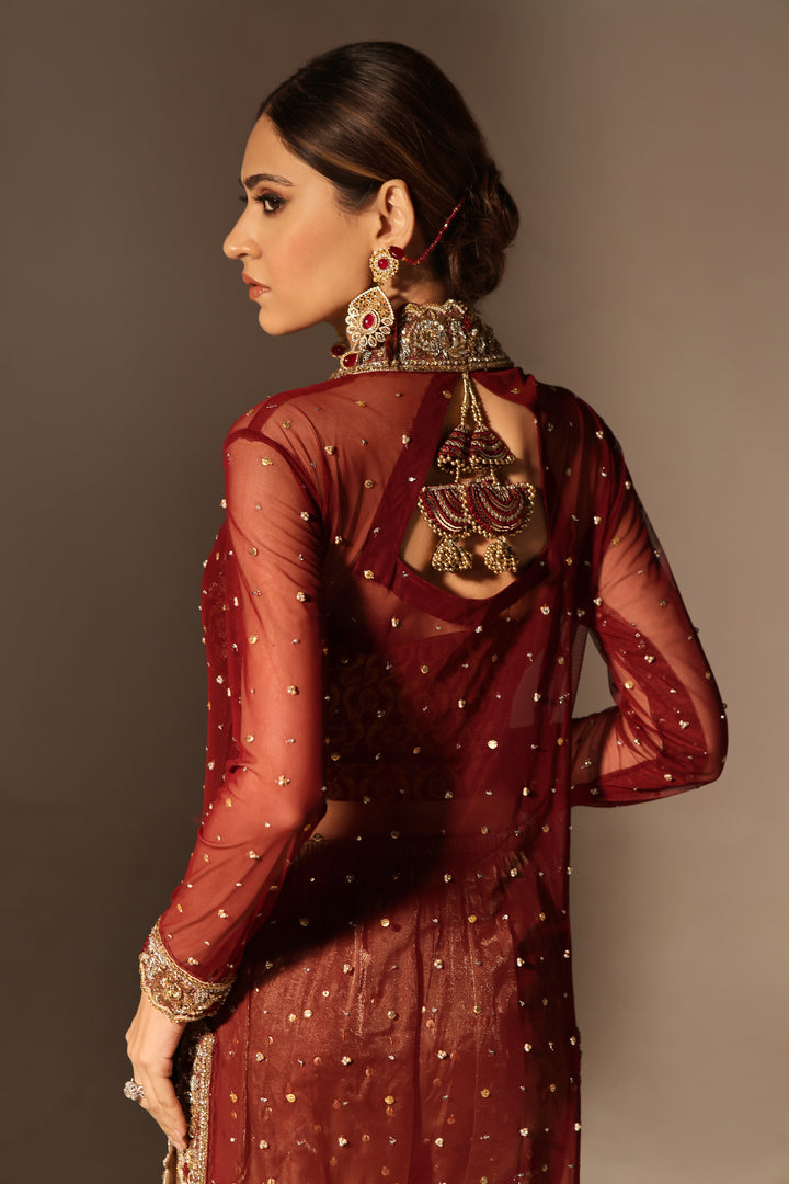  Step into timeless elegance with Gulabposh by Mona Imran, featuring a deep maroon kora net jacket adorned with exquisite antique gold appliquéd borders.