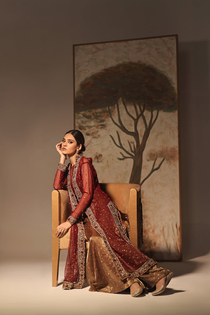  Step into timeless elegance with Gulabposh by Mona Imran, featuring a deep maroon kora net jacket adorned with exquisite antique gold appliquéd borders.