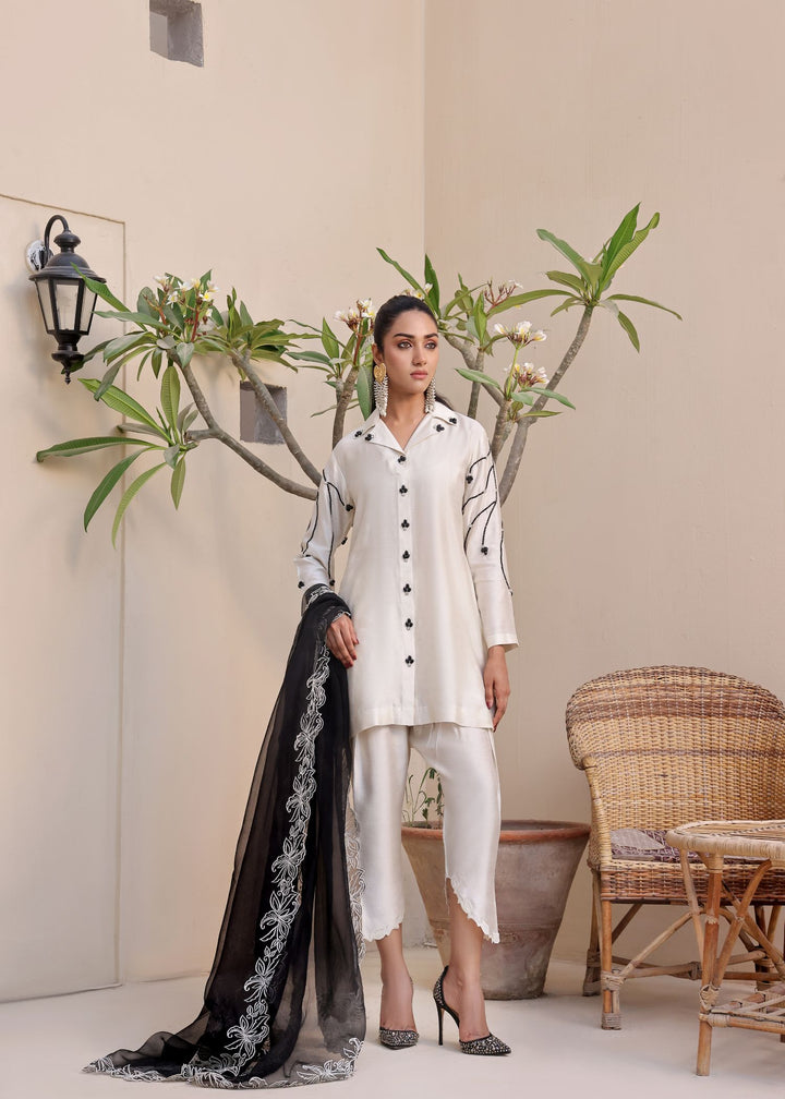  Step into elegance with Mona Imran's Noor, featuring a trendy front open shirt with black stones and intricate embroidery for a modern look.	