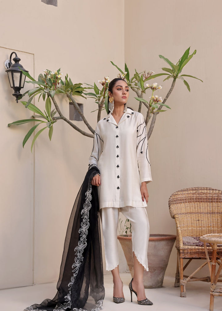  Step into elegance with Mona Imran's Noor, featuring a trendy front open shirt with black stones and intricate embroidery for a modern look.	